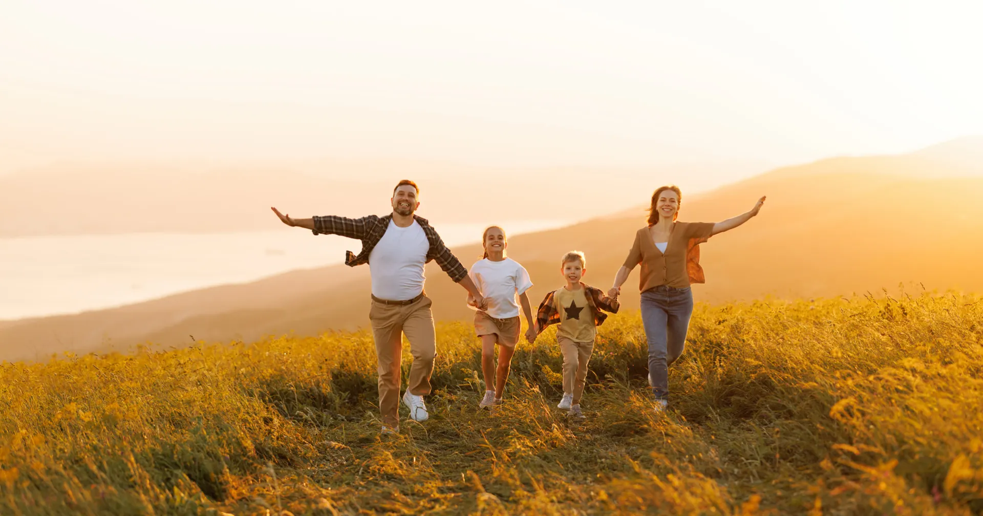 Gelukkige familie aan het rennen bij zonsondergang